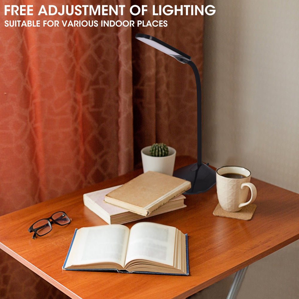 A contemporary desk illuminated by an adjustable desk lamp, complete with books, glasses, and a warming cup of coffee.